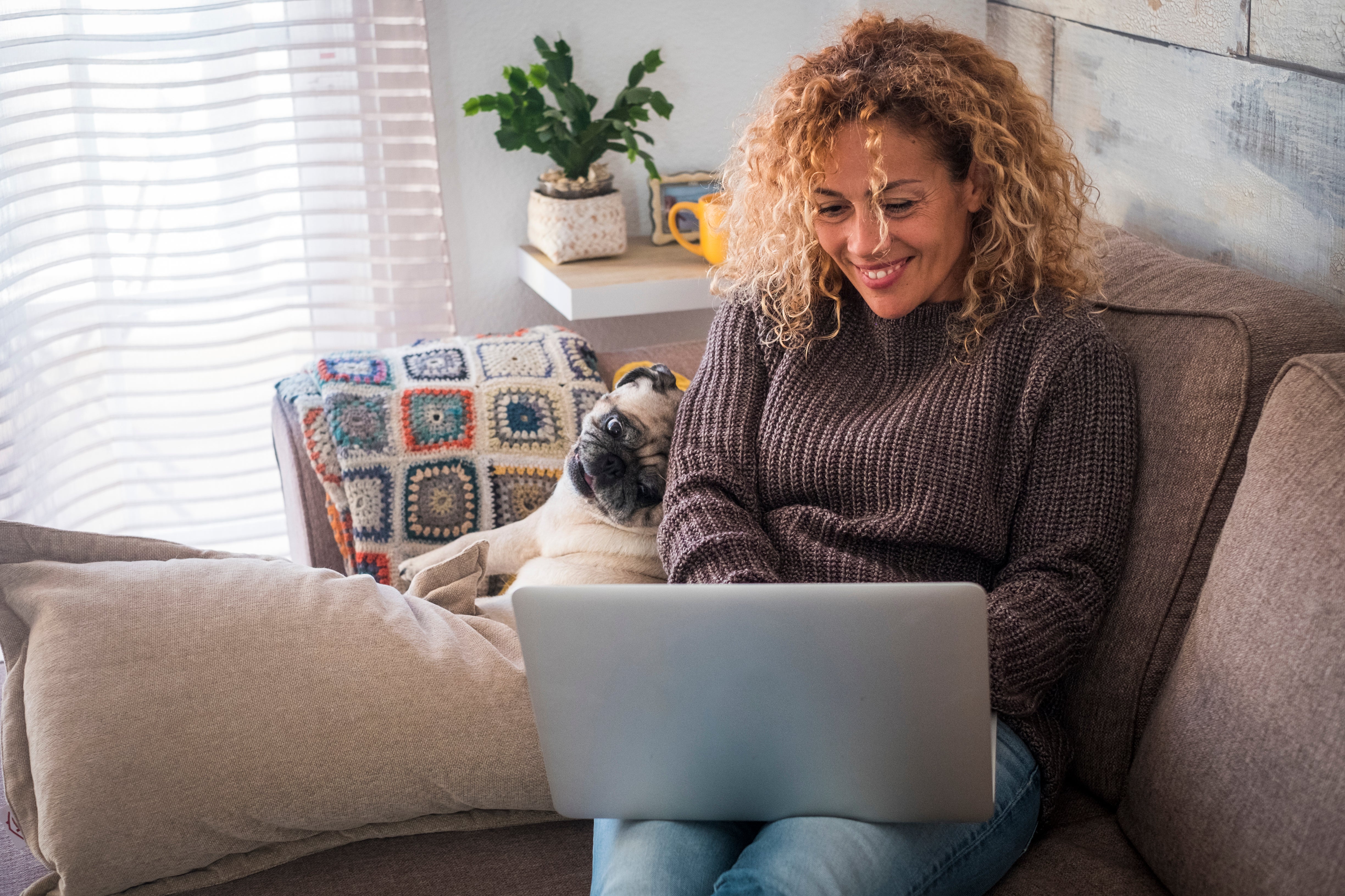 A woman enjoys time with her dog while working on her laptop